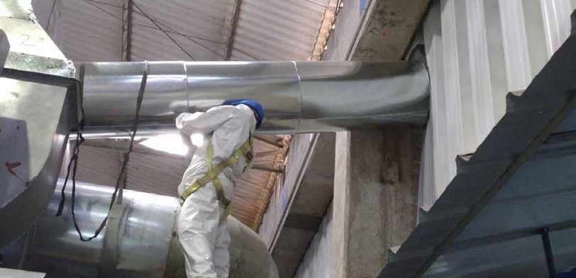 Técnico de MAX SERVICES limpiando ductos industriales con equipo de protección